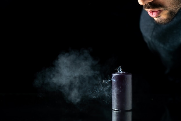 Free photo front view of dark candle getting fireless by male on a dark surface