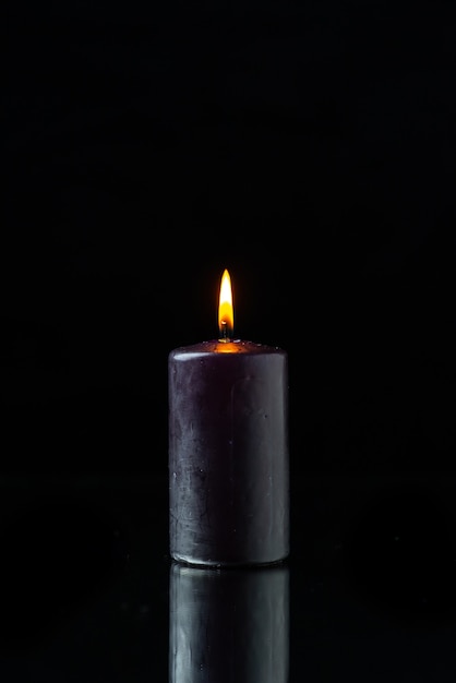 Front view of dark candle lighting on dark surface