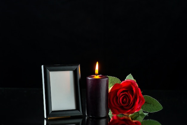 Free photo front view of dark candle with red rose and picture frame on dark surface