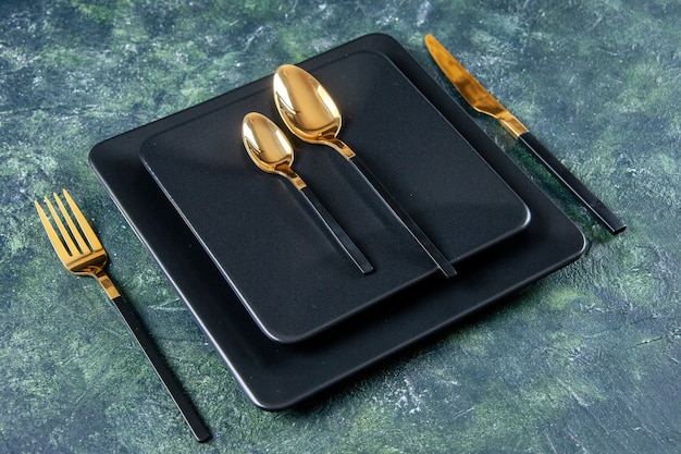 Free photo front view dark plates with golden spoons fork and knife on a dark-blue background