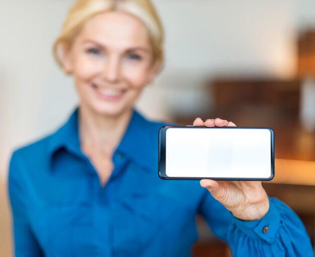 Front view of defocused smiley business woman holding smartphone