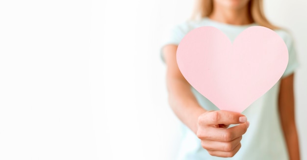 Front view of defocused woman holding heart shape with copy space