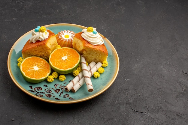 Free Photo front view delicious cake slices with pipe cookies and sliced tangerines on dark space