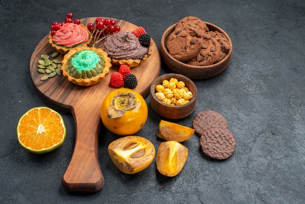 Free photo front view delicious cakes with biscuits and fruits on dark background