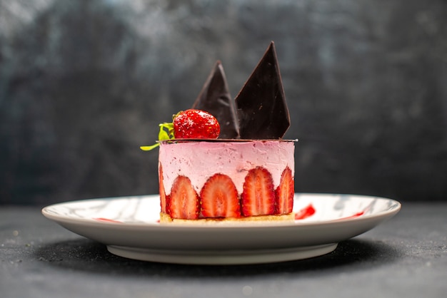 Free photo front view delicious cheesecake with strawberry and chocolate on oval plate on dark