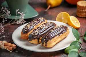 Free photo front view delicious choco eclairs on the dark background