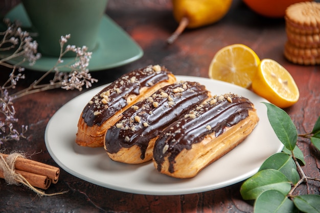 Front view delicious choco eclairs on the dark background