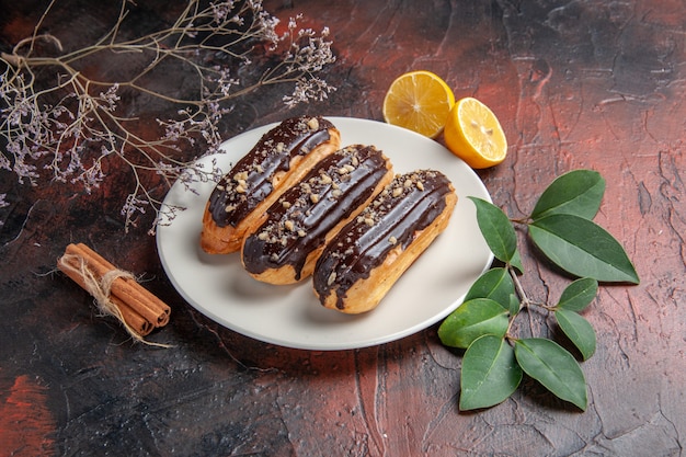 Free photo front view delicious choco eclairs inside plate on dark background