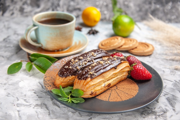 Front view delicious choco eclairs with tea on white table cookie dessert cake