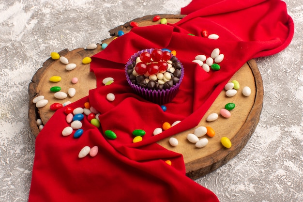 Free photo front view of delicious chocolate brownie with colorful candies on the light surface