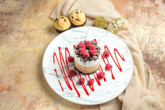 Front view delicious creamy cake inside plate with fresh raspberries on brown table