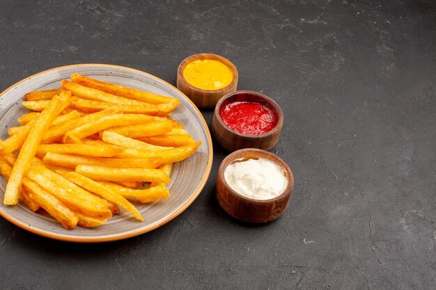 Front view delicious french fries with seasonings on a dark space