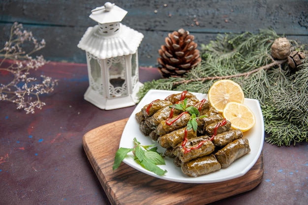 Free photo front view delicious leaf dolma with lemon slices on a dark space