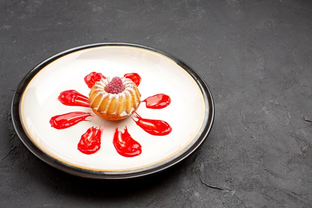 Front view delicious little cake with red icing inside plate on dark background tea sweet biscuit pie cookies sugar