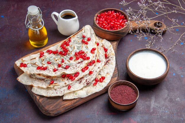 Front view delicious meat qutabs pitas with fresh red pomegranates on dark-purple surface dough meal food pita