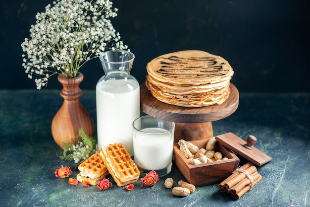 Front view delicious pancakes with fresh milk and nuts on dark-blue dessert pie honey cake breakfast sweet milk morning