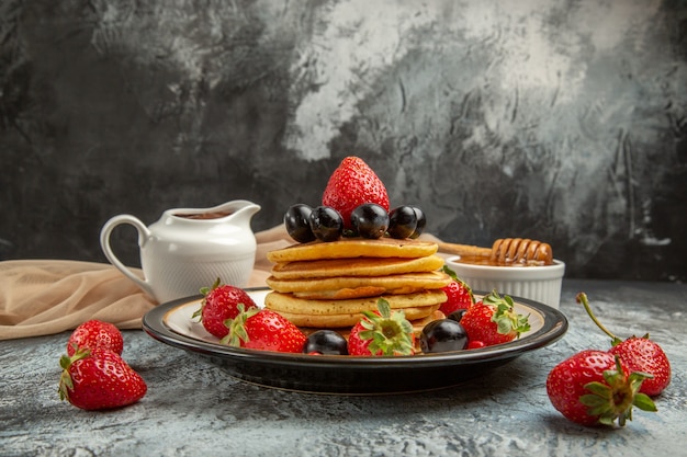 Front view delicious pancakes with honey and fruits on light surface sweet cake fruits