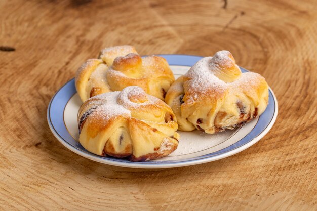 Front view delicious pastries with filling inside plate on the wooden table, sweet sugar cake bake pastry fruit