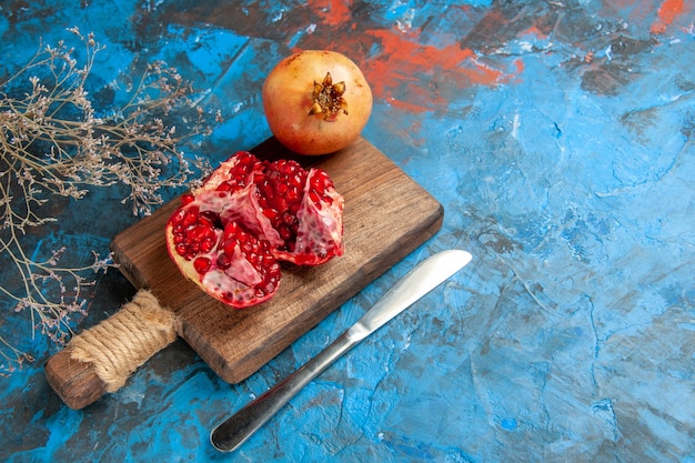 Free Photo front view delicious pomegranates on chopping board dinner knife on blue abstract background with free space