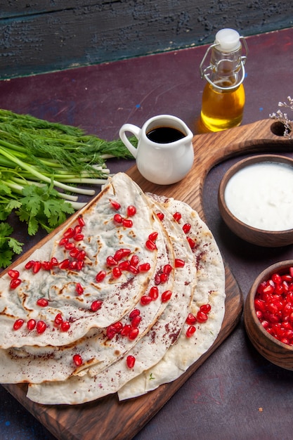 Front view delicious qutabs pitas with ground meat inside and with fresh pomegranates on dark surface dough pita meat meal food