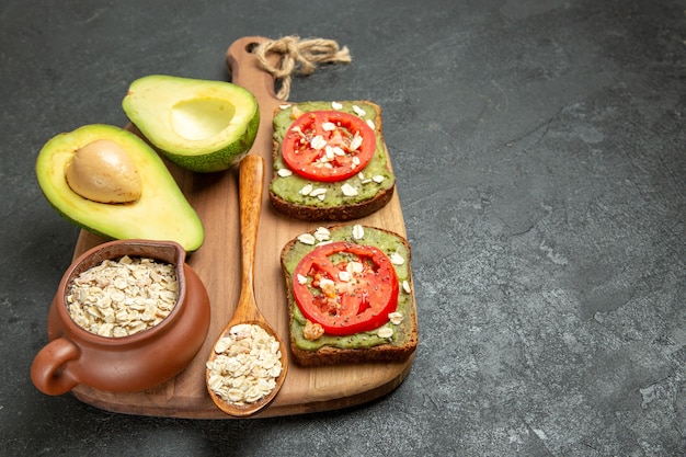 Front view delicious sandwiches with avocado and red tomatoes on a grey background lunch snack burger sandwich meal