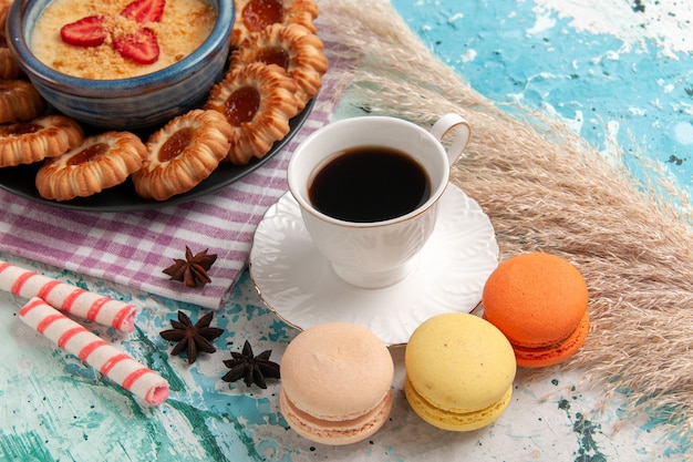 Front view delicious sugar cookies with macarons cup of coffee and strawberry dessert on blue surface cookie biscuit sweet dessert sugar cake