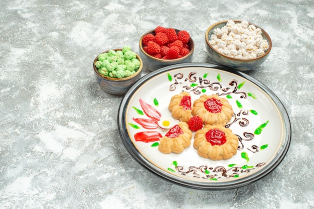 Free photo front view delicious sweet cookies with red jelly and candies on white space