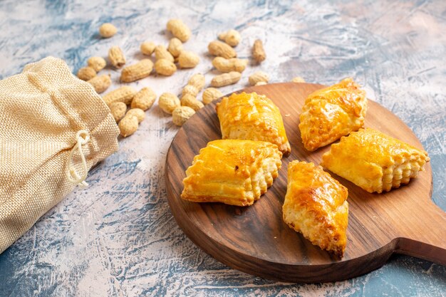 Front view of delicious sweet pastries with peanuts on blue surface