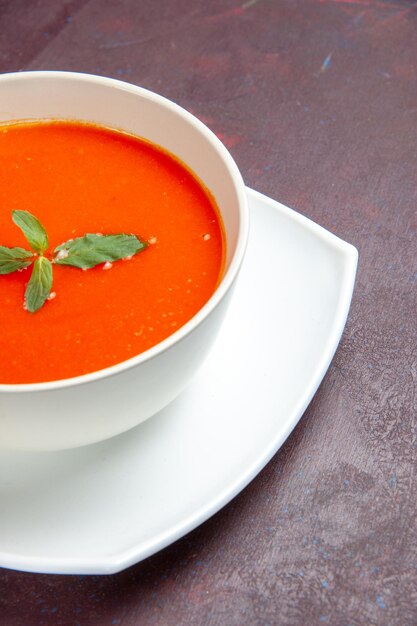 Front view delicious tomato soup tasty dish with single leaf inside plate on dark desk dish sauce tomato color soup