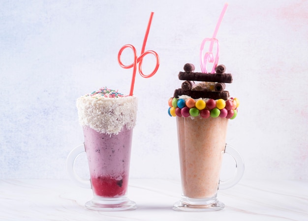 Free photo front view of dessert glasses with straws and colorful candy