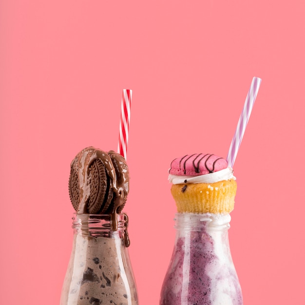 Front view of desserts with biscuit and muffin with straws