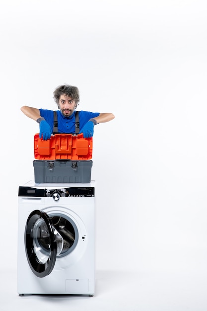 Front view determined repairman putting tools bag on washing machine on white space