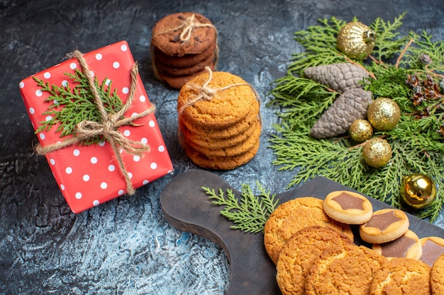 Front view different delicious biscuits with present on light-dark surface