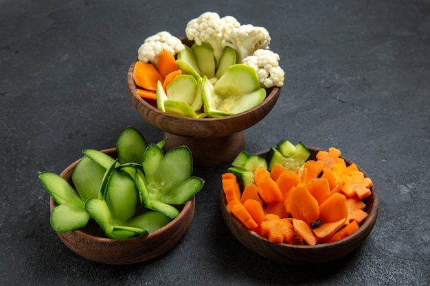 Free photo front view different designed vegetables inside pots on grey space