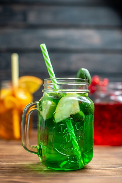 Front view different fresh juices inside cans on brown wooden desk