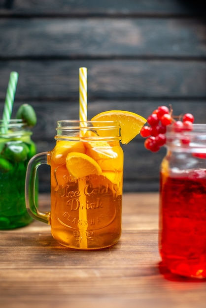 Free photo front view different fresh juices inside cans on brown wooden desk