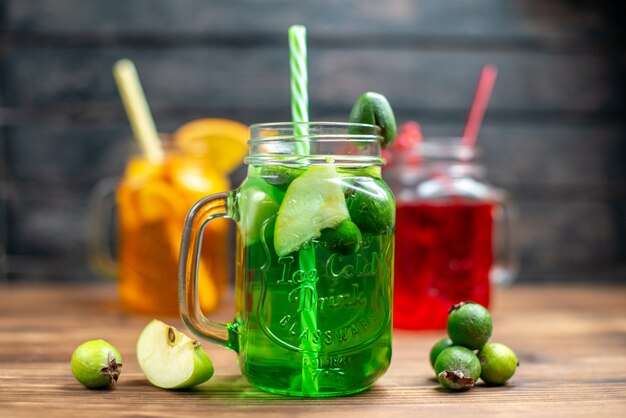 Front view different fruity juice inside cans on brown wooden desk r