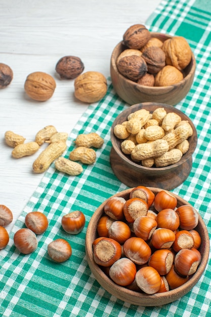 Front view different nuts peanuts hazelnuts and walnuts on white surface