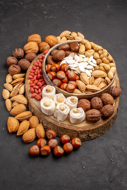 Front view of different nuts with sweet confitures on grey surface