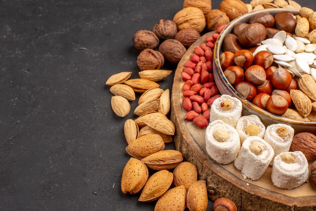 Front view of different nuts with white confitures on grey surface