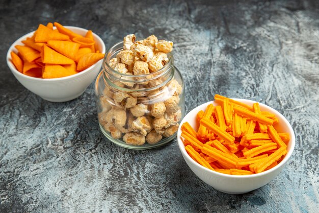 Front view different snacks popcorn rusks and cips on dark background