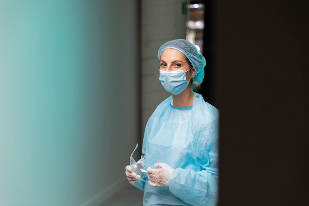 Free photo front view doctor in protective wear holding her goggles