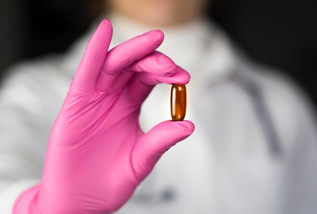 Front view of doctor with surgical glove holding pill