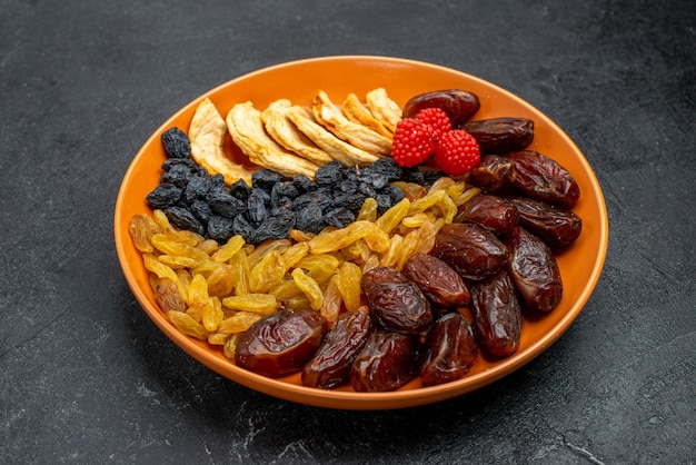 Front view dried fruits with raisins inside plate on the grey space