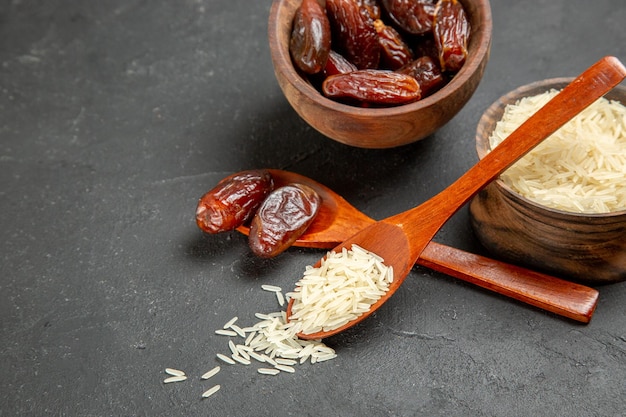 Free photo front view dried raisins with raw rice on the dark surface raisin dry fruit