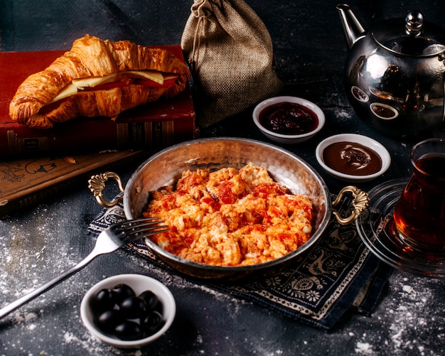 Front view eggs red tomatoes fried along with fresh bread olives and tea on the bright surface