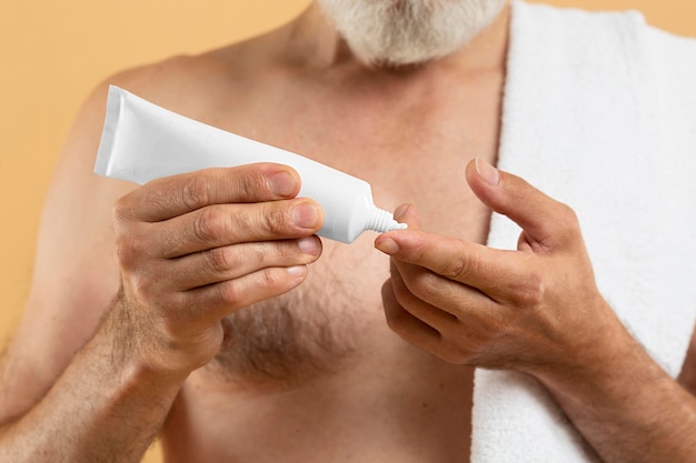 Front view of elder bearded man using cream