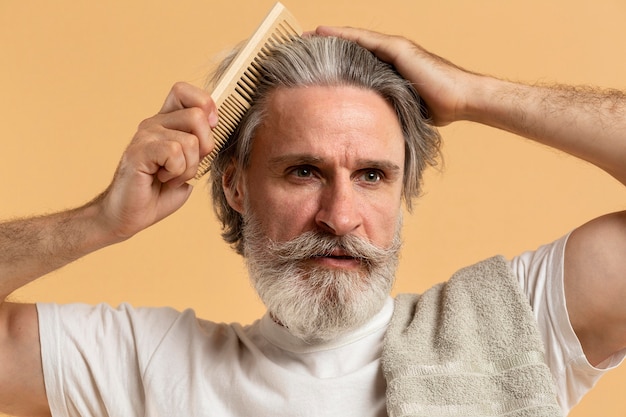 Free photo front view of elder man with beard combing his hair