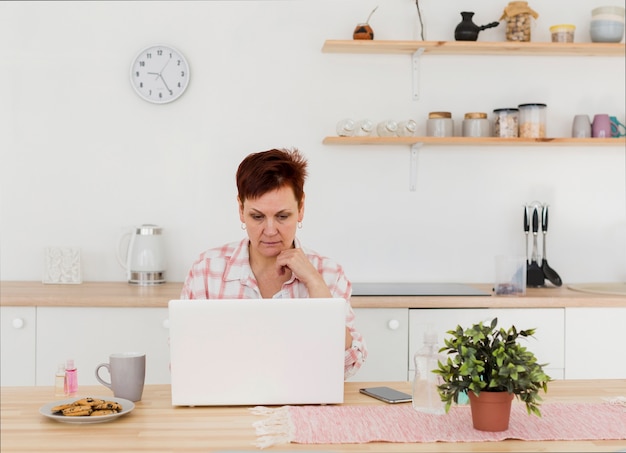 Free photo front view of elder woman at home on her laptop