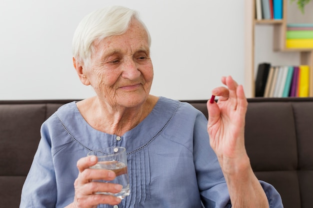 Free Photo front view of elder woman taking her daily pill